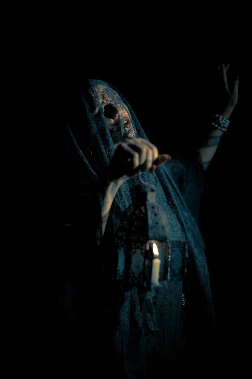 Free Eerie portrait of a veiled figure holding a lantern in darkness. Stock Photo