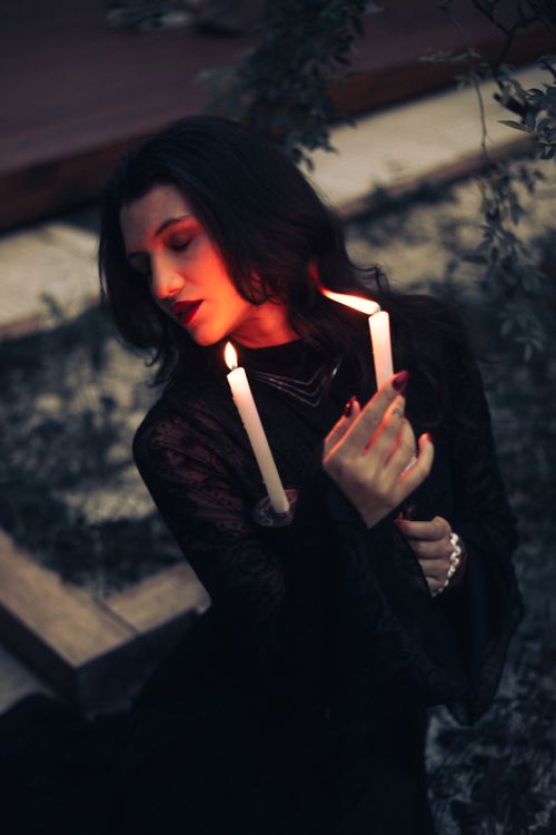 Free Portrait of a woman holding candles, creating a mysterious and dramatic atmosphere. Stock Photo