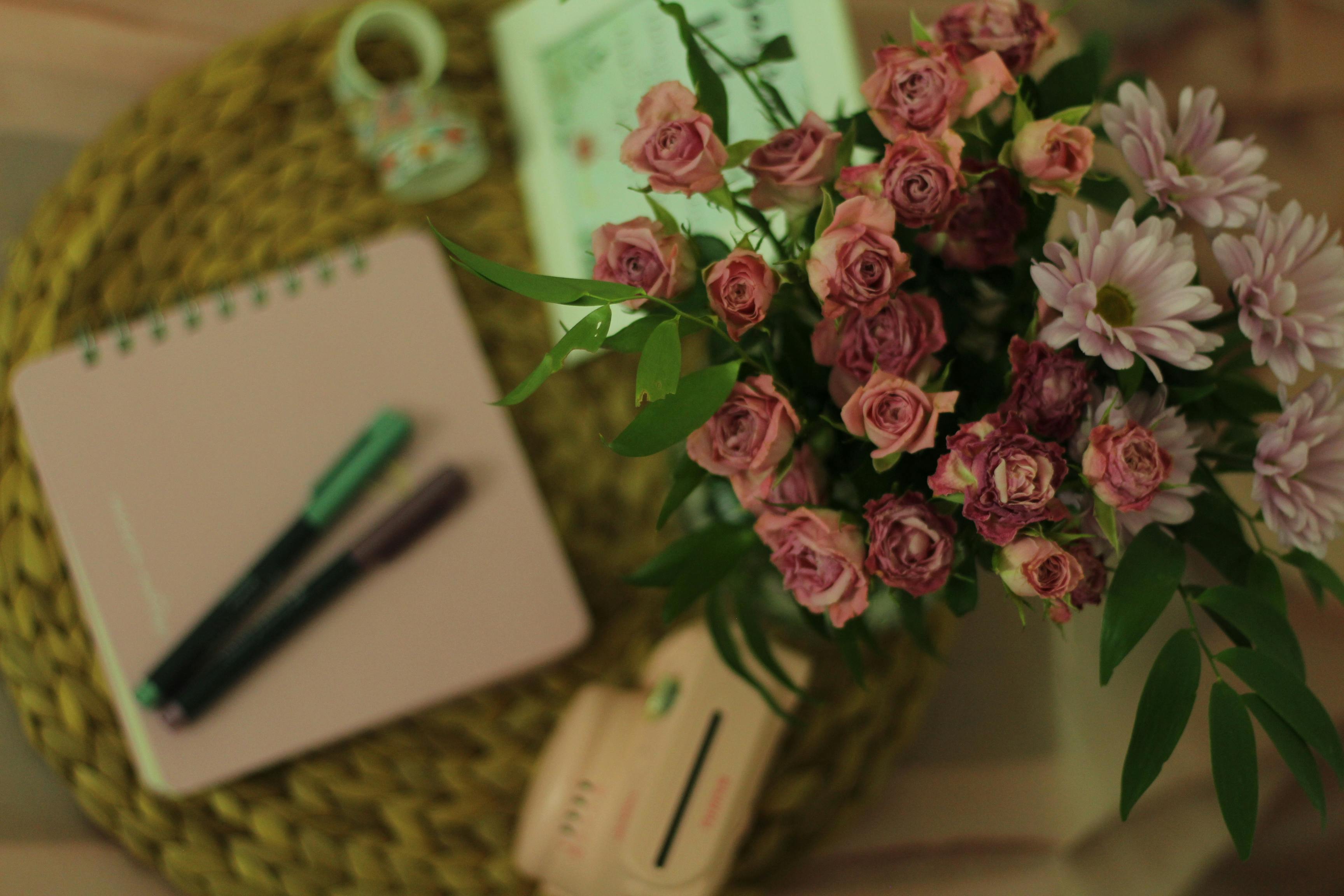 免費 舒適的工作空間，木桌上擺放著優雅的粉紅玫瑰和雛菊，營造出溫馨的氛圍。 圖庫相片