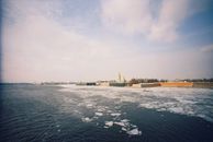 Panoramic view of Peter and Paul Fortress across a partially frozen Neva River in winter.