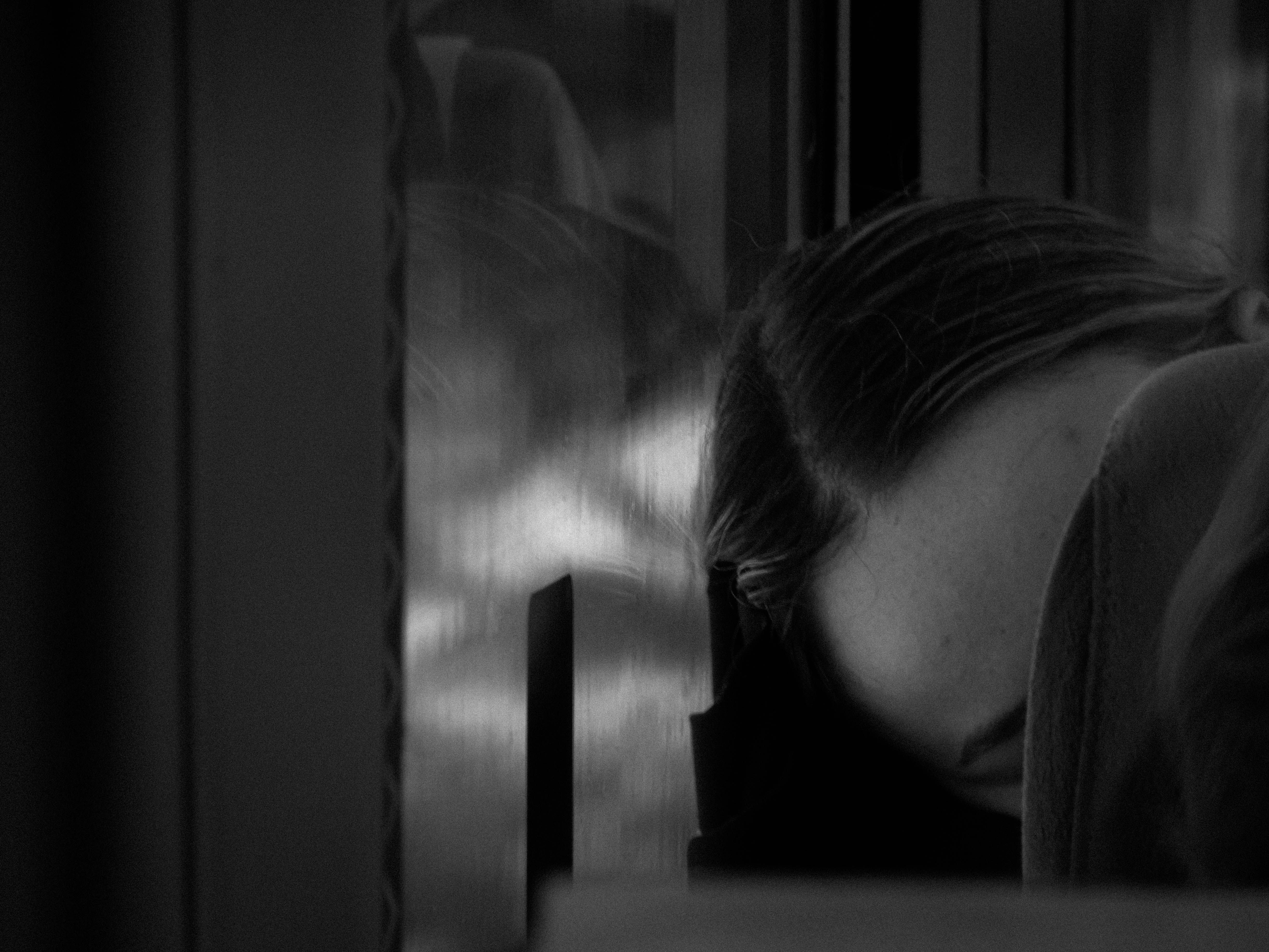 A person resting their head on a train window, captured in black and white, evokes a serene and reflective mood.