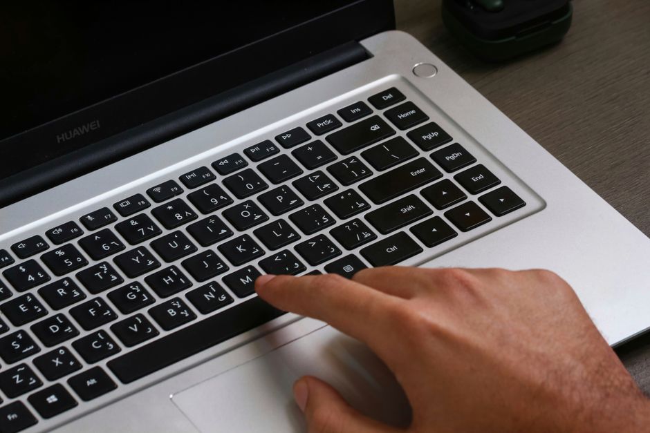 Fingers on a laptop keyboard with Arabic text, showcasing modern technology.