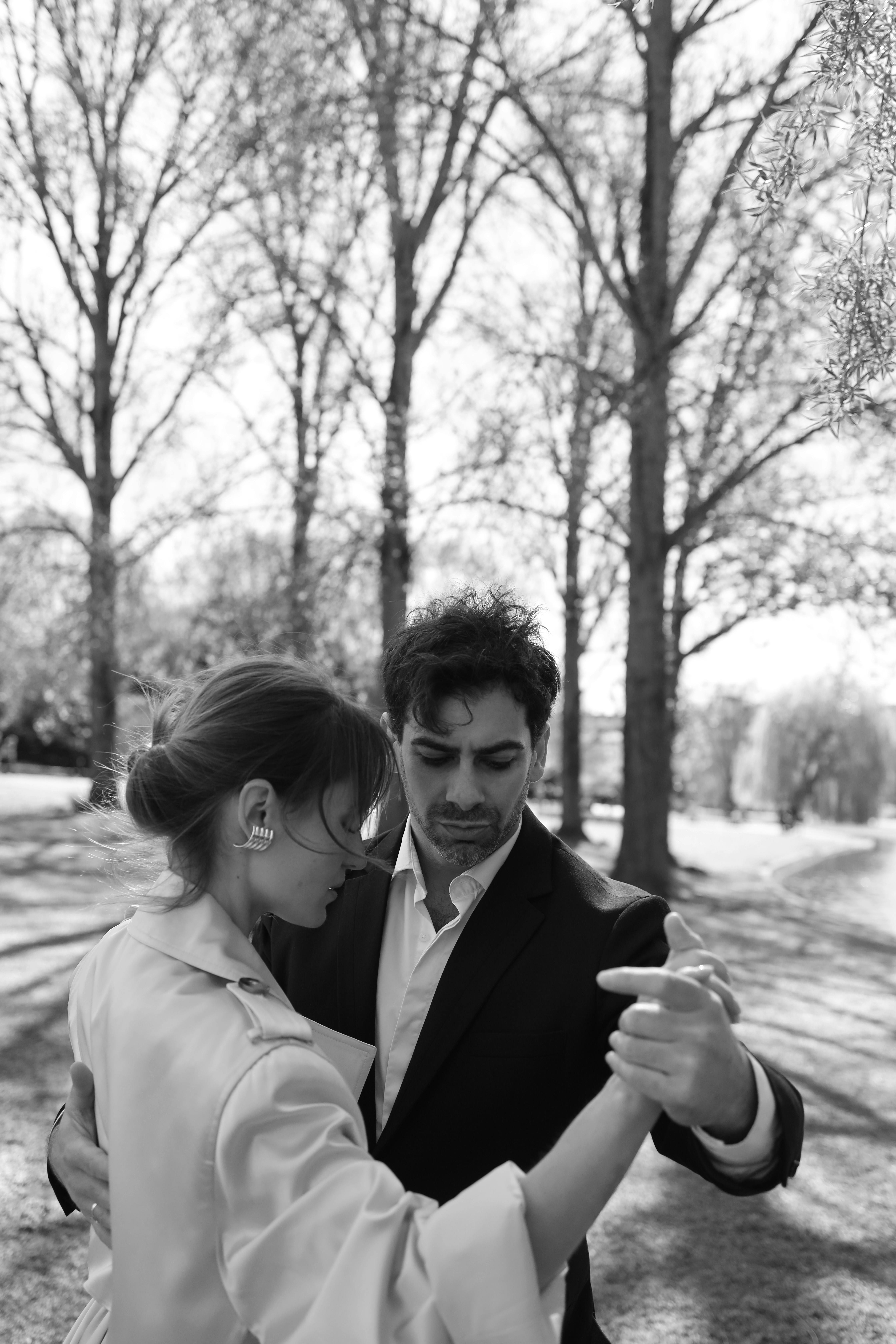 A couple elegantly dancing outdoors in a black and white photograph, capturing timeless romance.