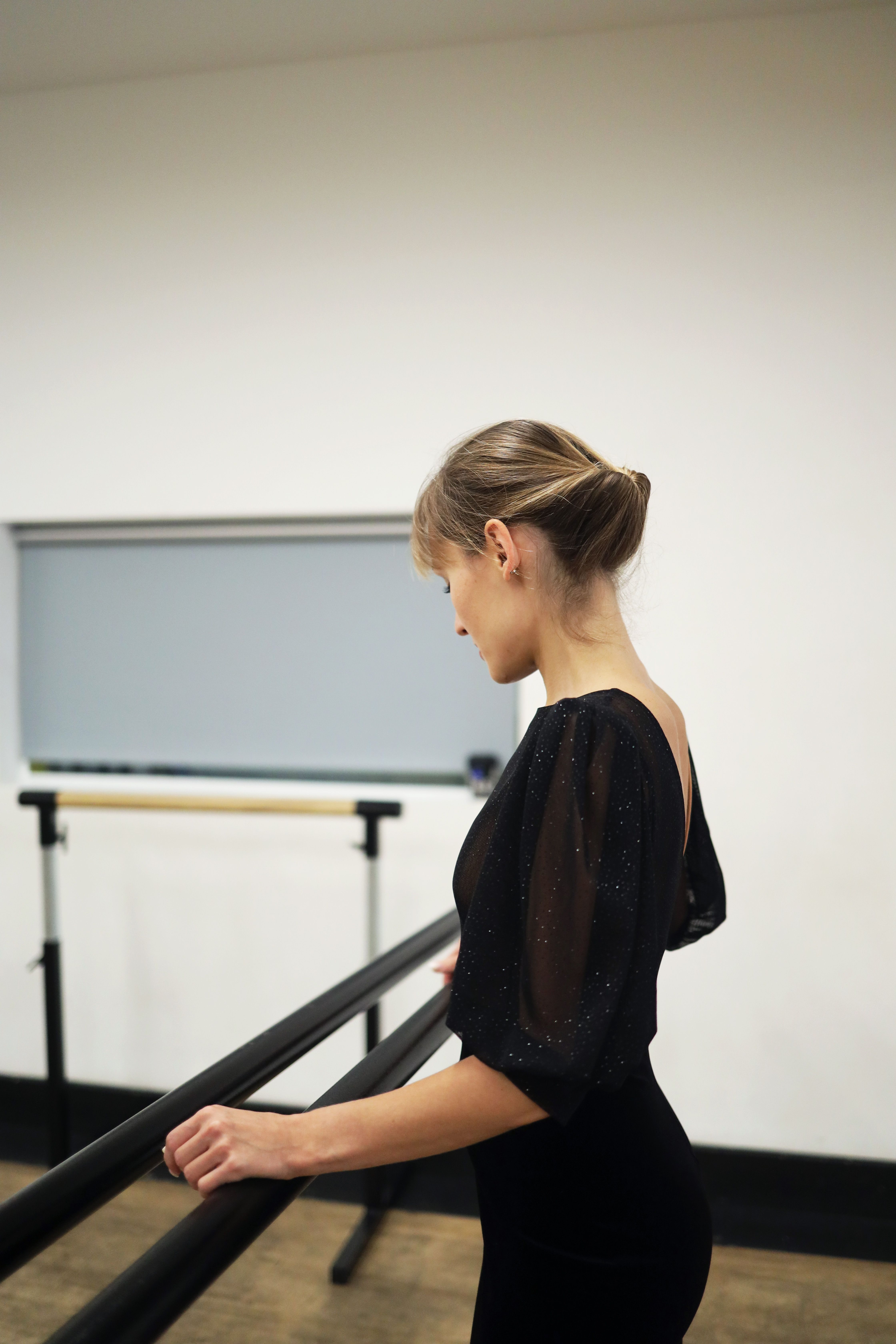 Ballet dancer rehearsing at barre in a dance studio, showcasing grace and concentration.