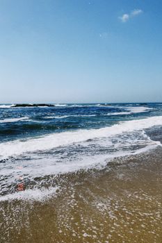 Tranquil beach scene featuring gentle ocean waves under a clear blue sky.