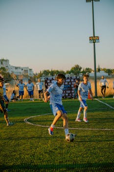 Young soccer players in action during an outdoor match at sunset, showcasing teamwork.