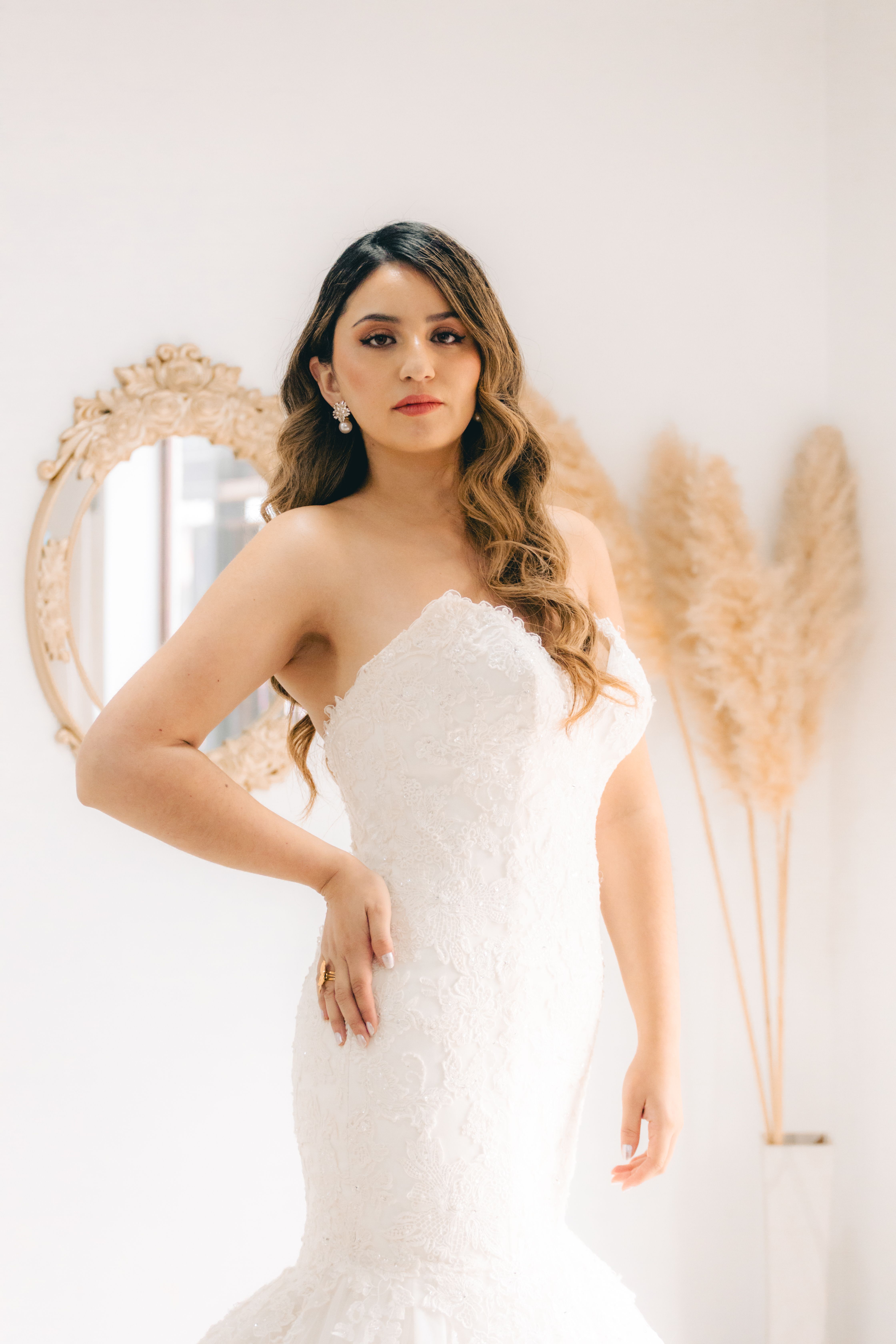Elegant bride in a white gown poses in a bright and stylish interior setting.