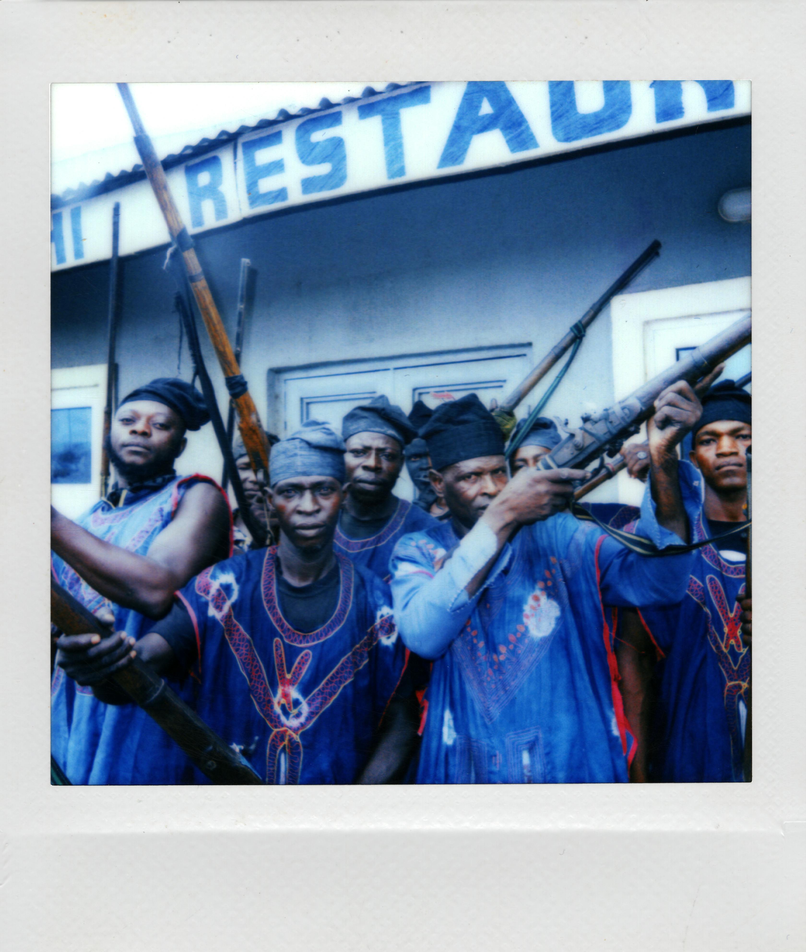 A group of men in traditional clothing holding rifles outside a building.