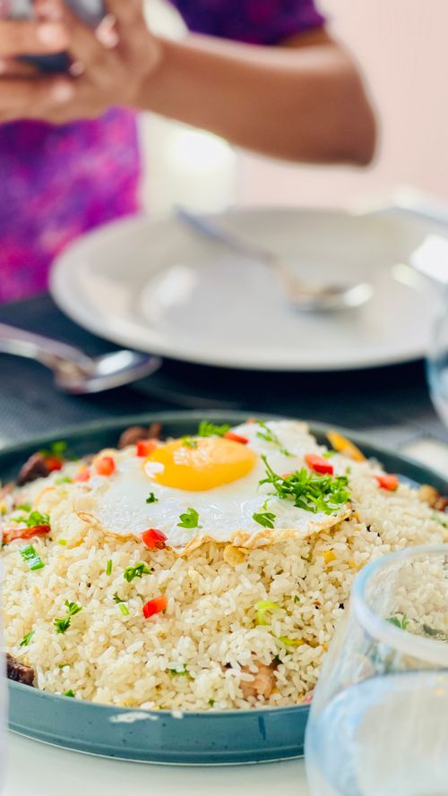 Free Close-up of fried rice topped with a sunny side up egg, garnished with vegetables. Stock Photo