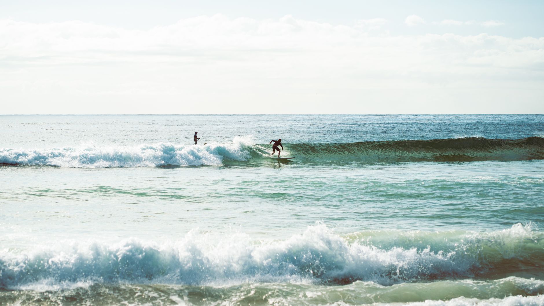 Surfing adventure on sunny Wollongong beach with surfers riding the waves of the Pacific Ocean.