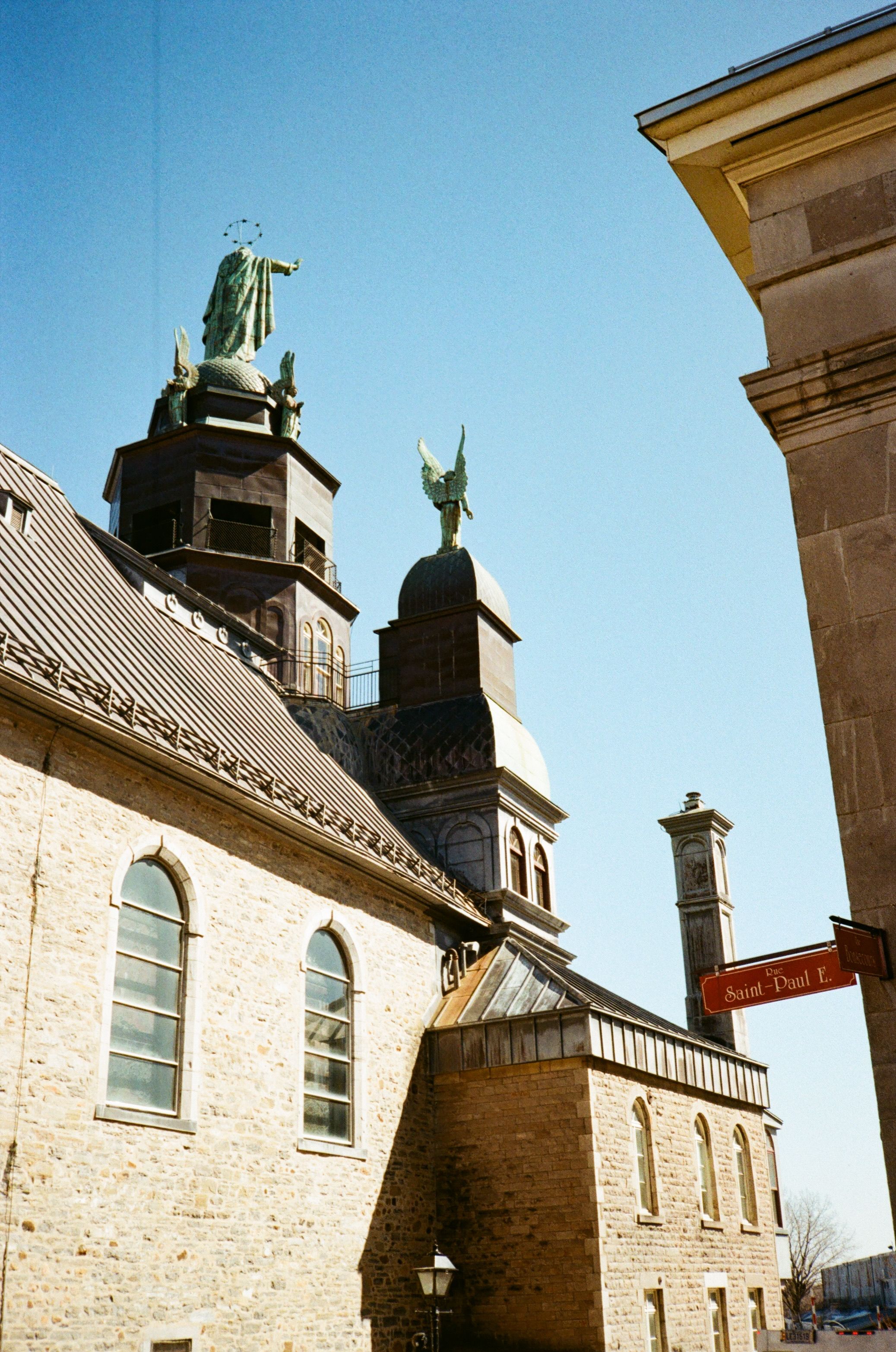 Statues atop a historic church in Old Montreal under a clear blue sky.
