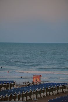 Beautiful evening view of Mar del Plata beach with blue tents and gentle waves in Argentina.
