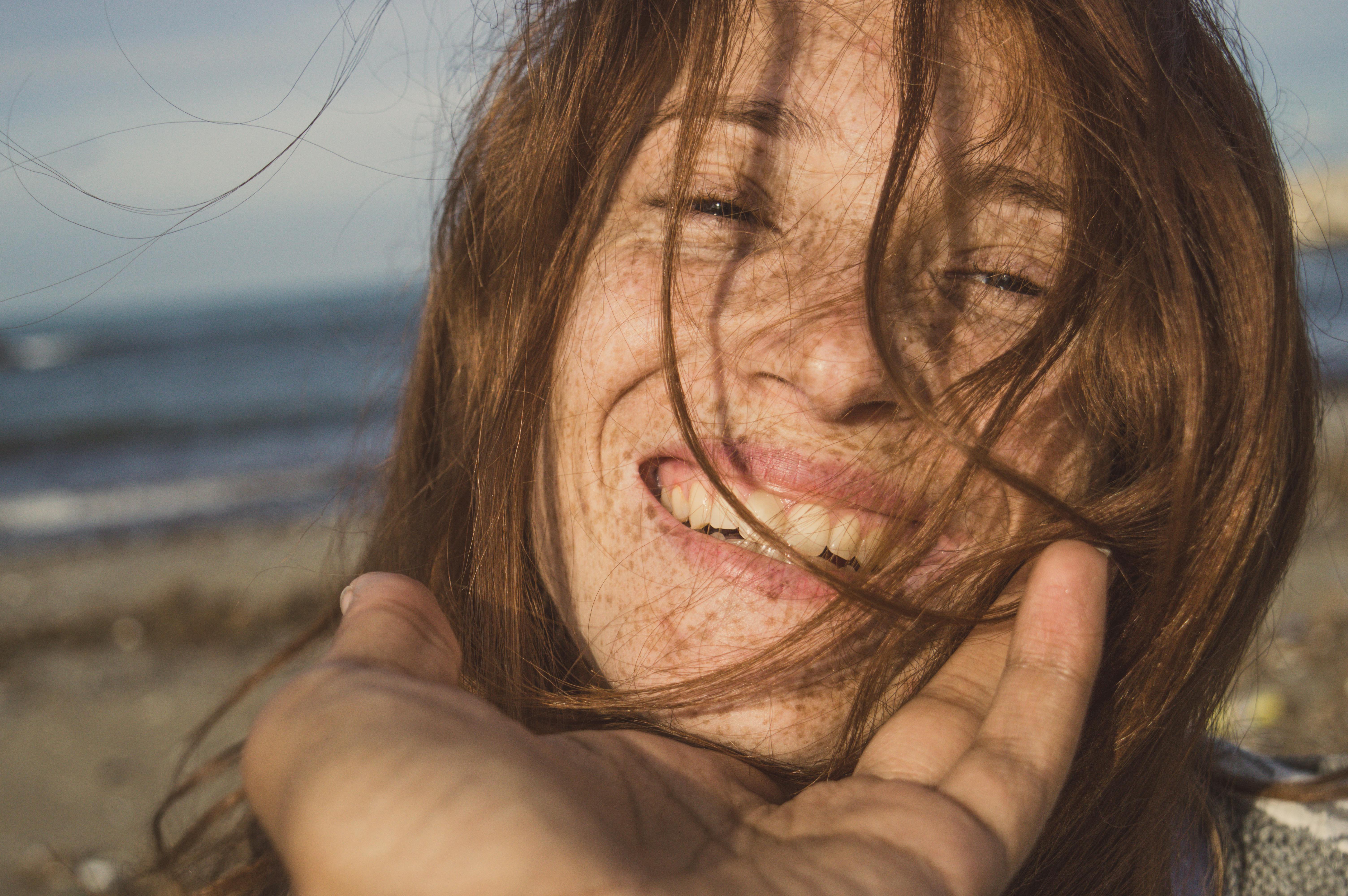 woman with brown hair covering her face with her hand