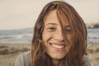 阳光明媚的日子里，一位红发女子在海滩上微笑的特写肖像