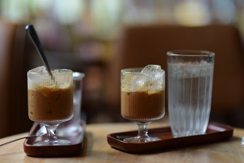 Free Iced coffee and water in glass tumblers on a wooden table indoors, creating a calm atmosphere. Stock Photo