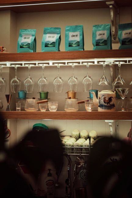 A well-organized coffee bar shelf showcasing various glassware, coffee supplies, and equipment.