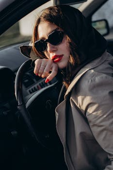 Chic woman with sunglasses sitting in a luxury car, exuding elegance.