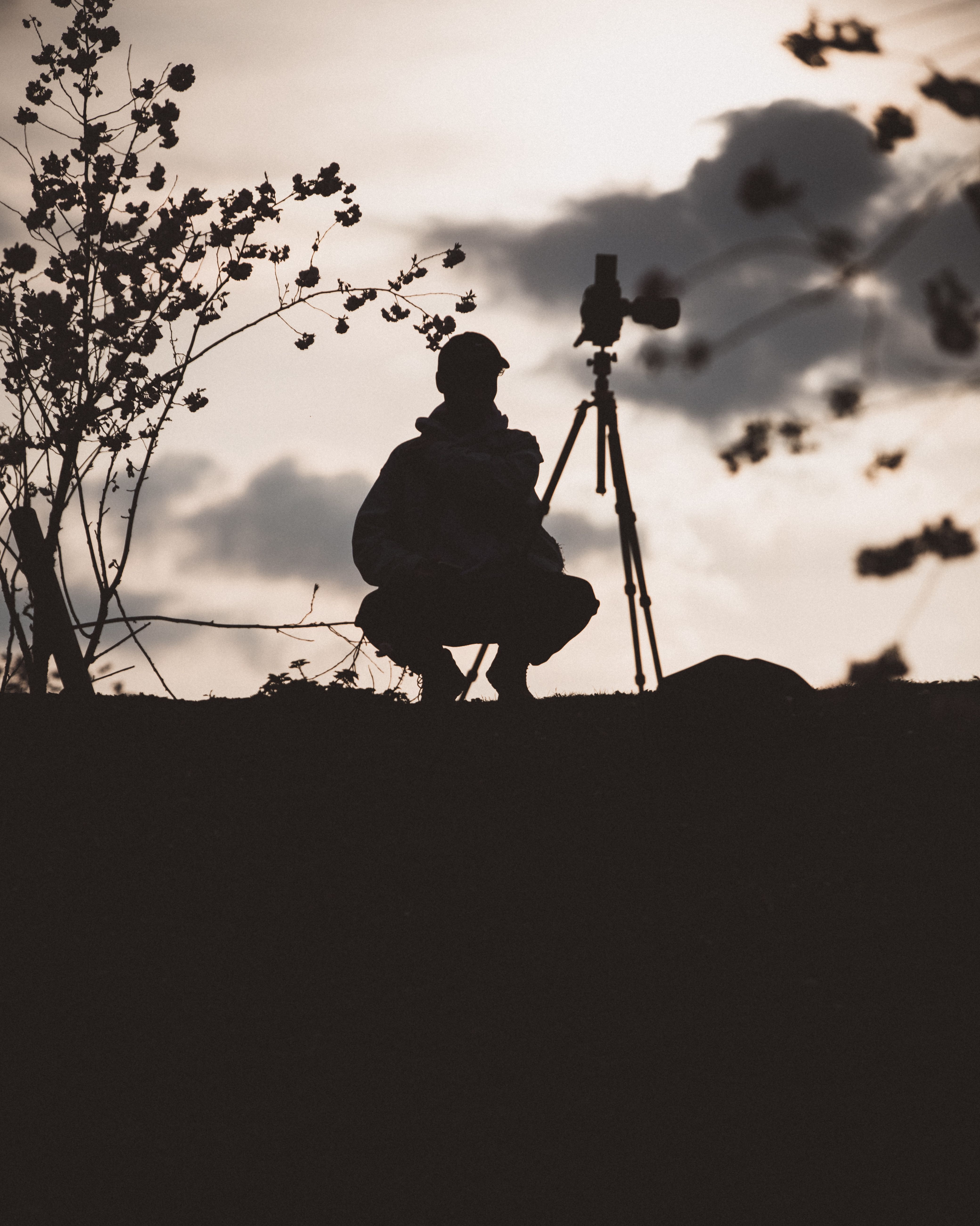 A contemplative silhouette of a photographer setting up a camera at sunset in Munich.