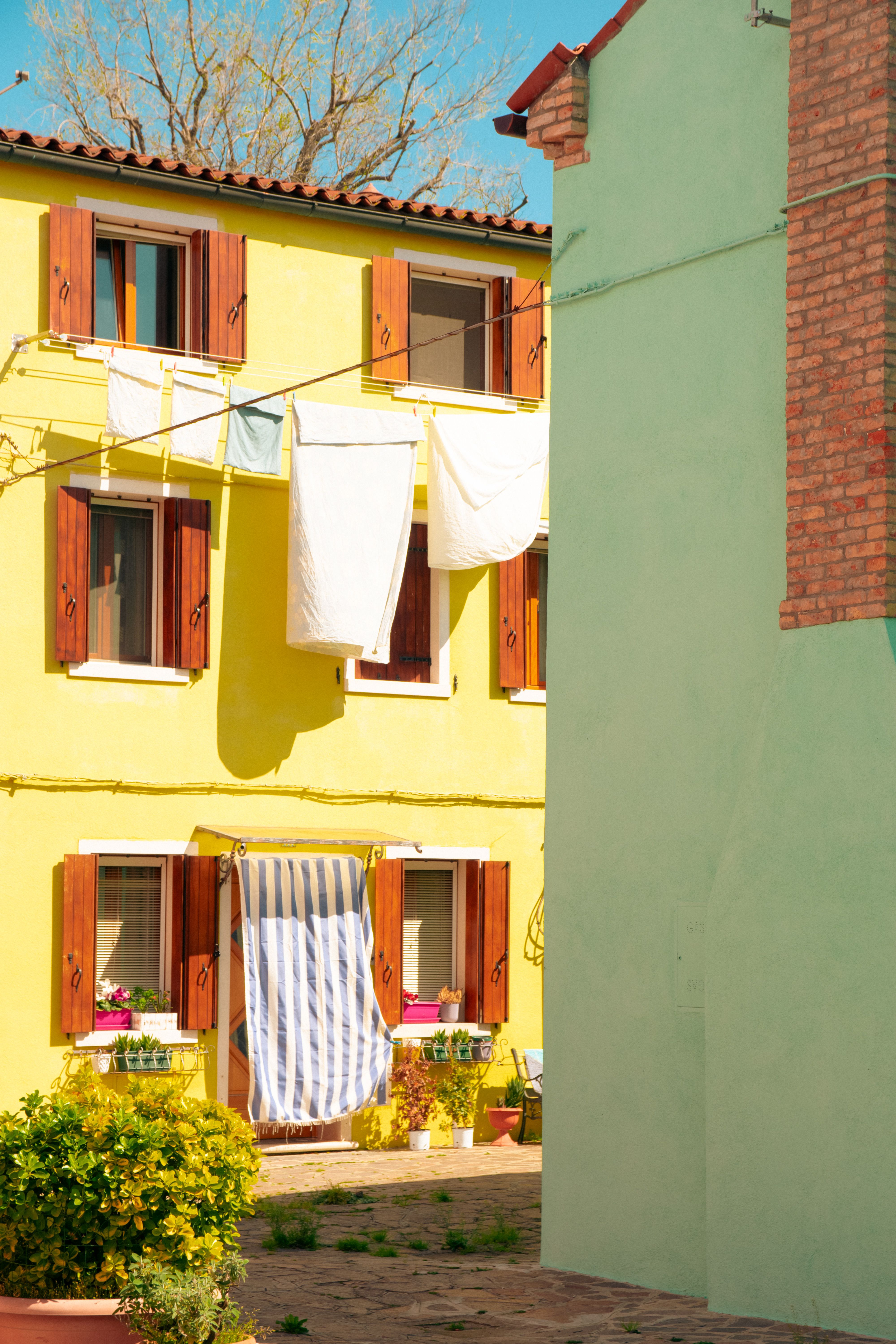 Vibrant yellow Venetian building with rustic charm and hanging laundry, capturing the essence of Burano, Venice.