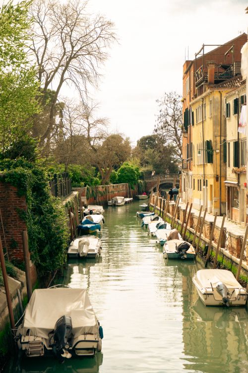 Free Charming Venice canal lined with boats and historic buildings capturing classic Italian architecture. Stock Photo