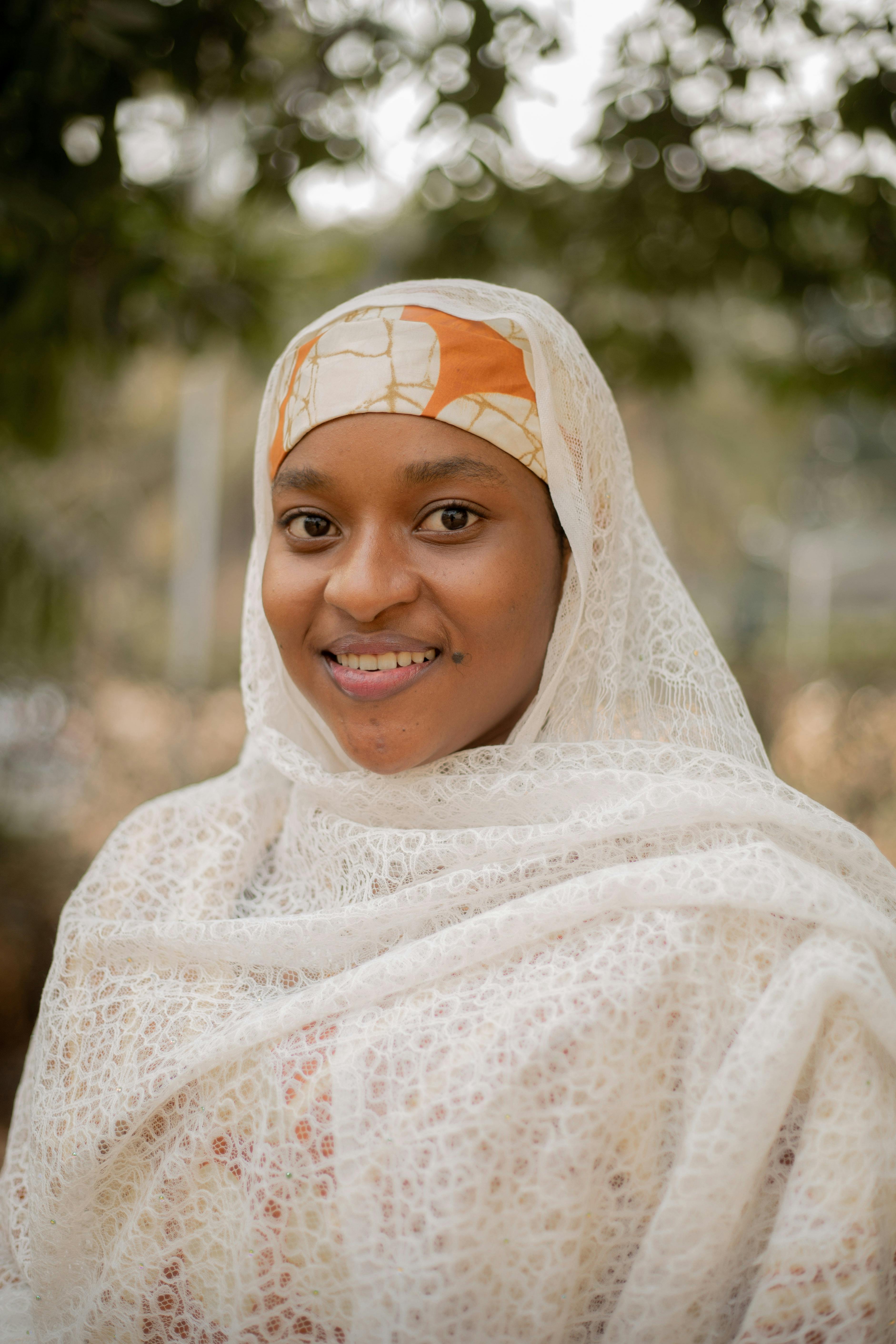 Smiling African woman wearing traditional attire outdoors in Abuja, Nigeria.