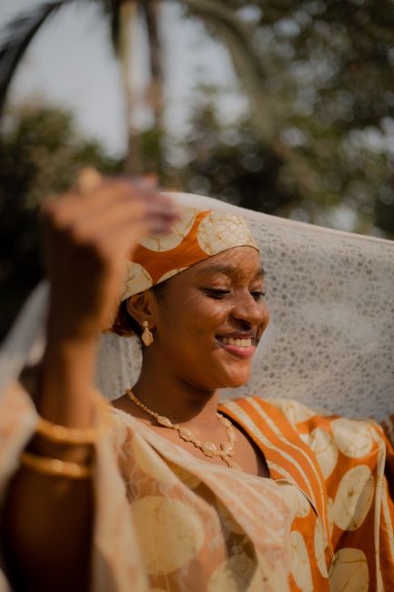 A vibrant portrait of an African woman in traditional clothing, captured outdoors in beautiful sunlight.