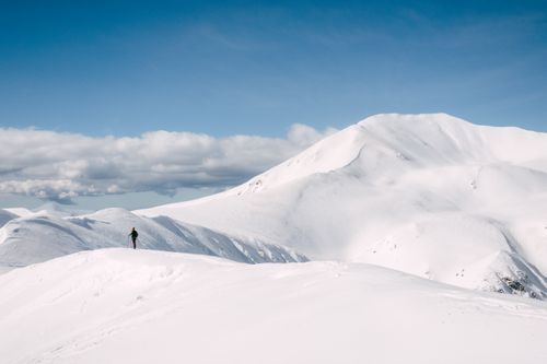 Free Solo hiker on a snowy mountain summit against a clear blue sky, perfect for adventure themes. Stock Photo