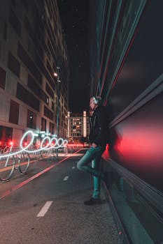 在奥斯陆，一名男子倚靠着墙壁，墙上的灯光痕迹在夜间城市景观中形成了动态的图案