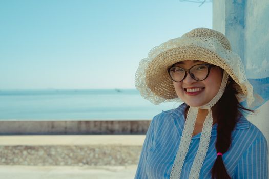A woman wearing a straw hat smiles by the seaside in Bình Thuận, Vietnam.