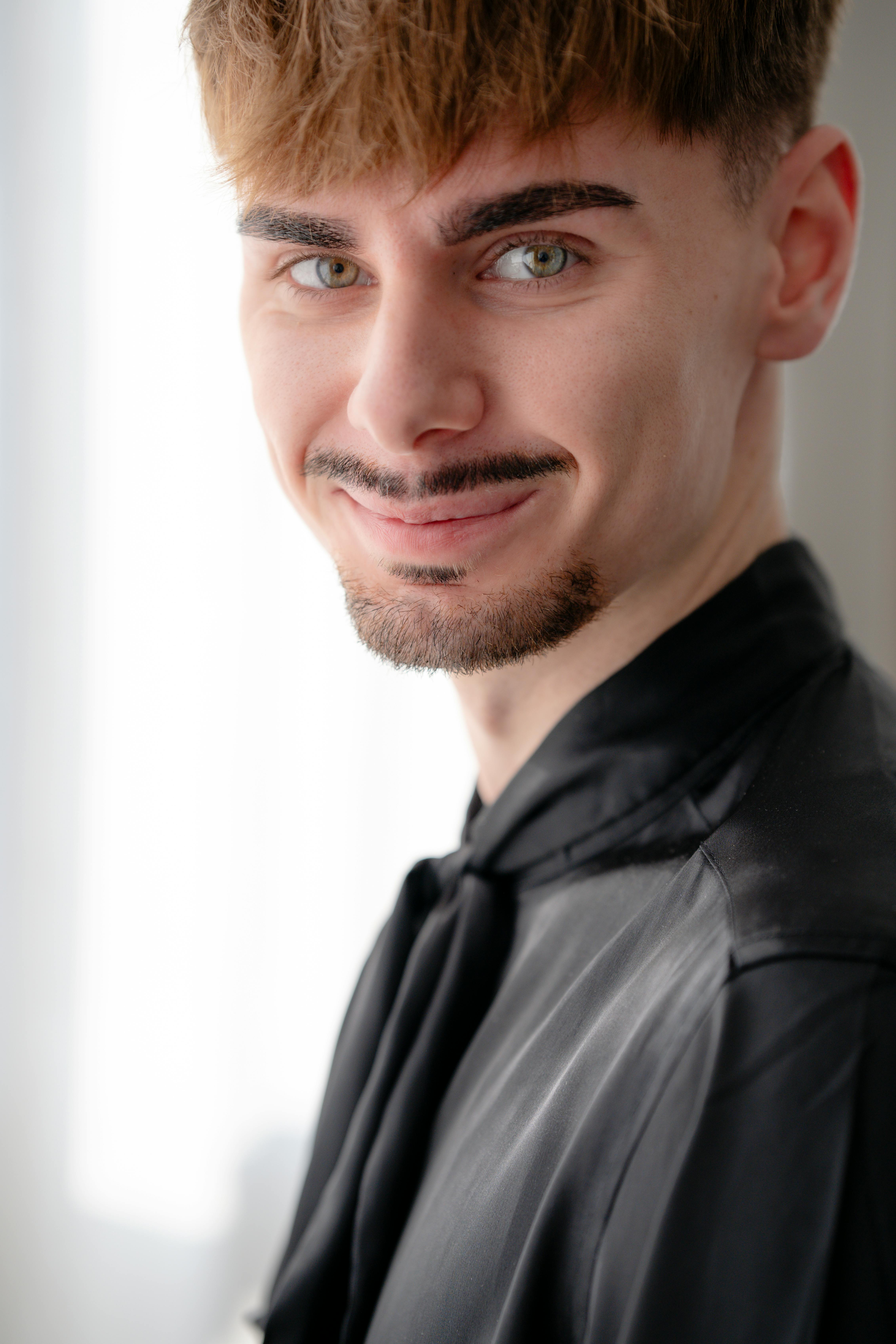 Portrait of a young man with a friendly smile and fashionable attire.