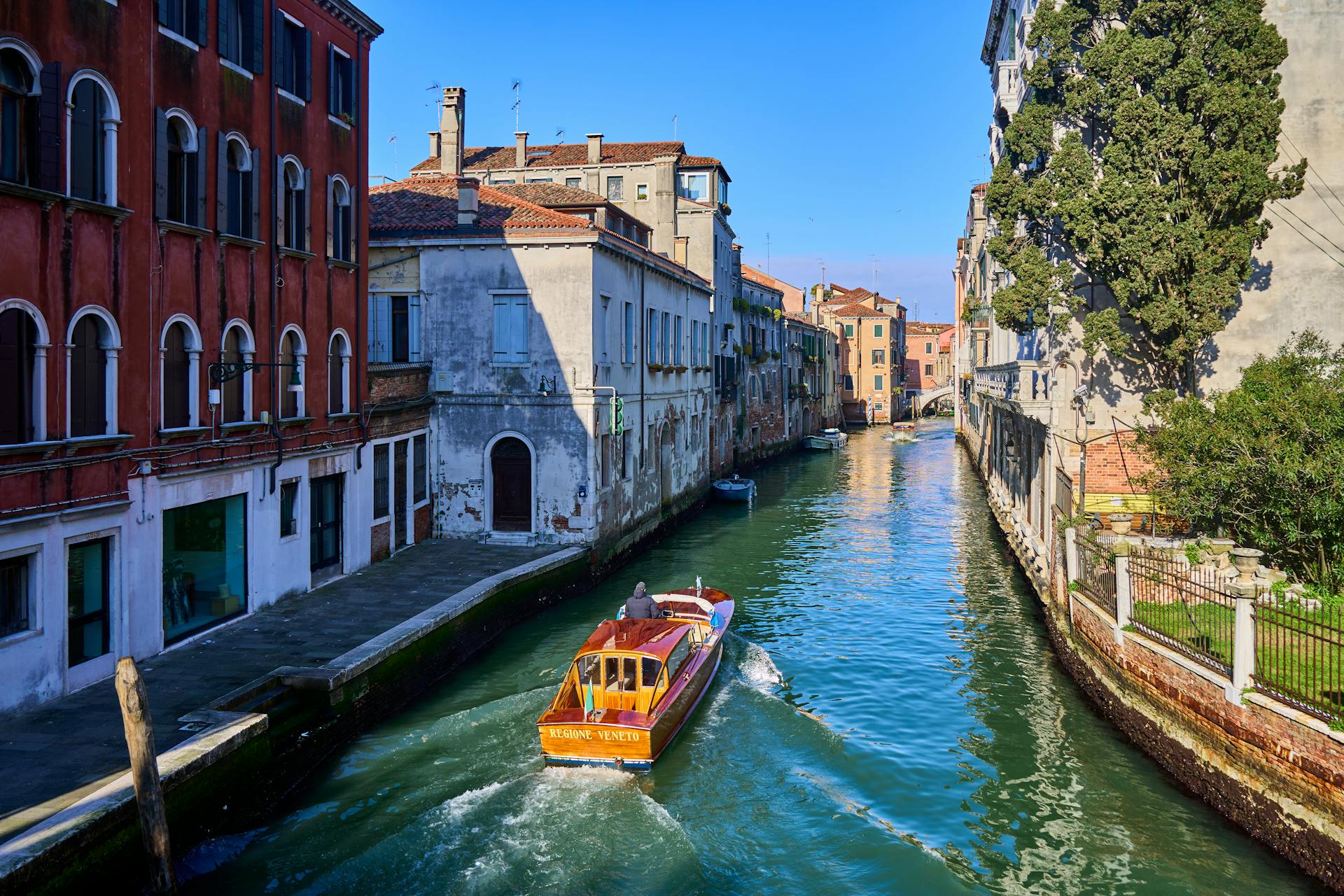 A vibrant day in Venice with a water taxi navigating a picturesque canal.