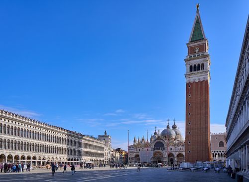 Free St. Mark's Campanile and Basilica in Venice's iconic St. Mark's Square under a clear blue sky. Stock Photo