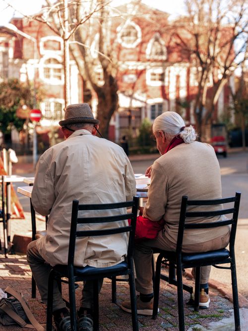 Free Senior couple sitting at an outdoor cafe, enjoying a sunny day. Stock Photo