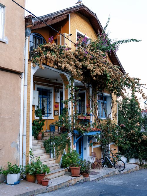 Free Picturesque yellow house with balcony, vibrant flowers, and rustic charm. Stock Photo