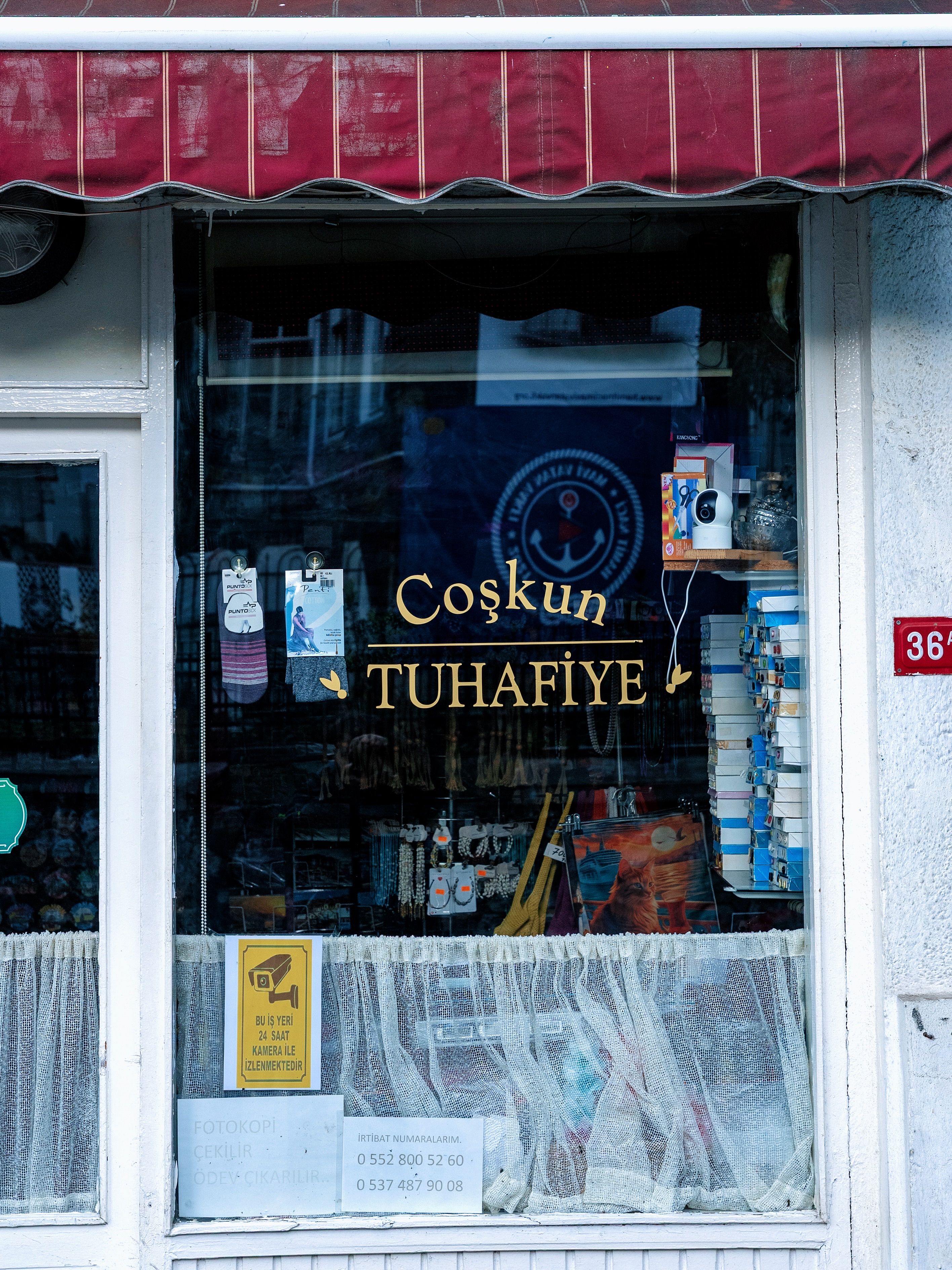 Window view of a Turkish haberdashery shop with products on display and signage.