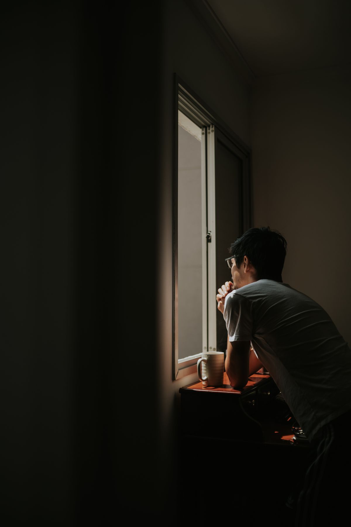 Man leaning on a windowsill, lost in thought