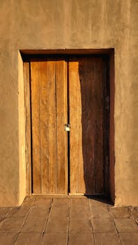 A rustic wooden door bathed in warm sunset light, showcasing weathered textures and earthy tones.
