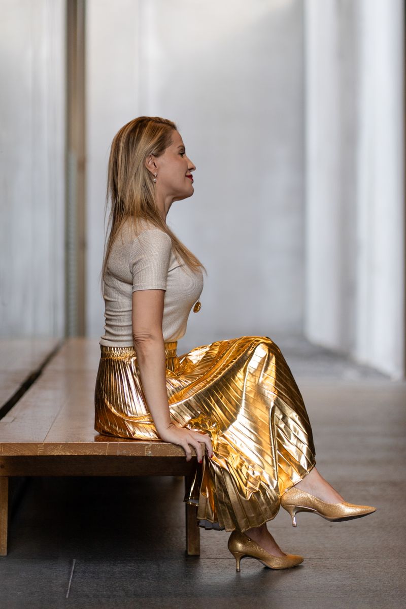 Elegant woman in golden skirt sitting indoors