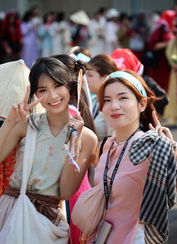 Two young Asian women smiling and posing cheerfully at an outdoor event.