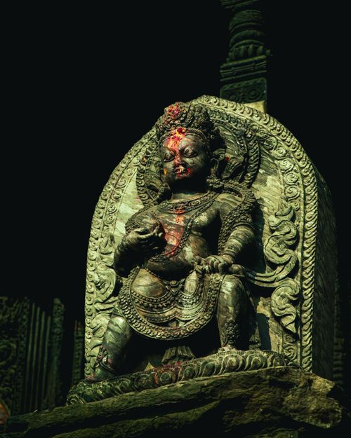 Free Detailed stone statue of a Hindu deity adorned with red markings, under dramatic lighting. Stock Photo