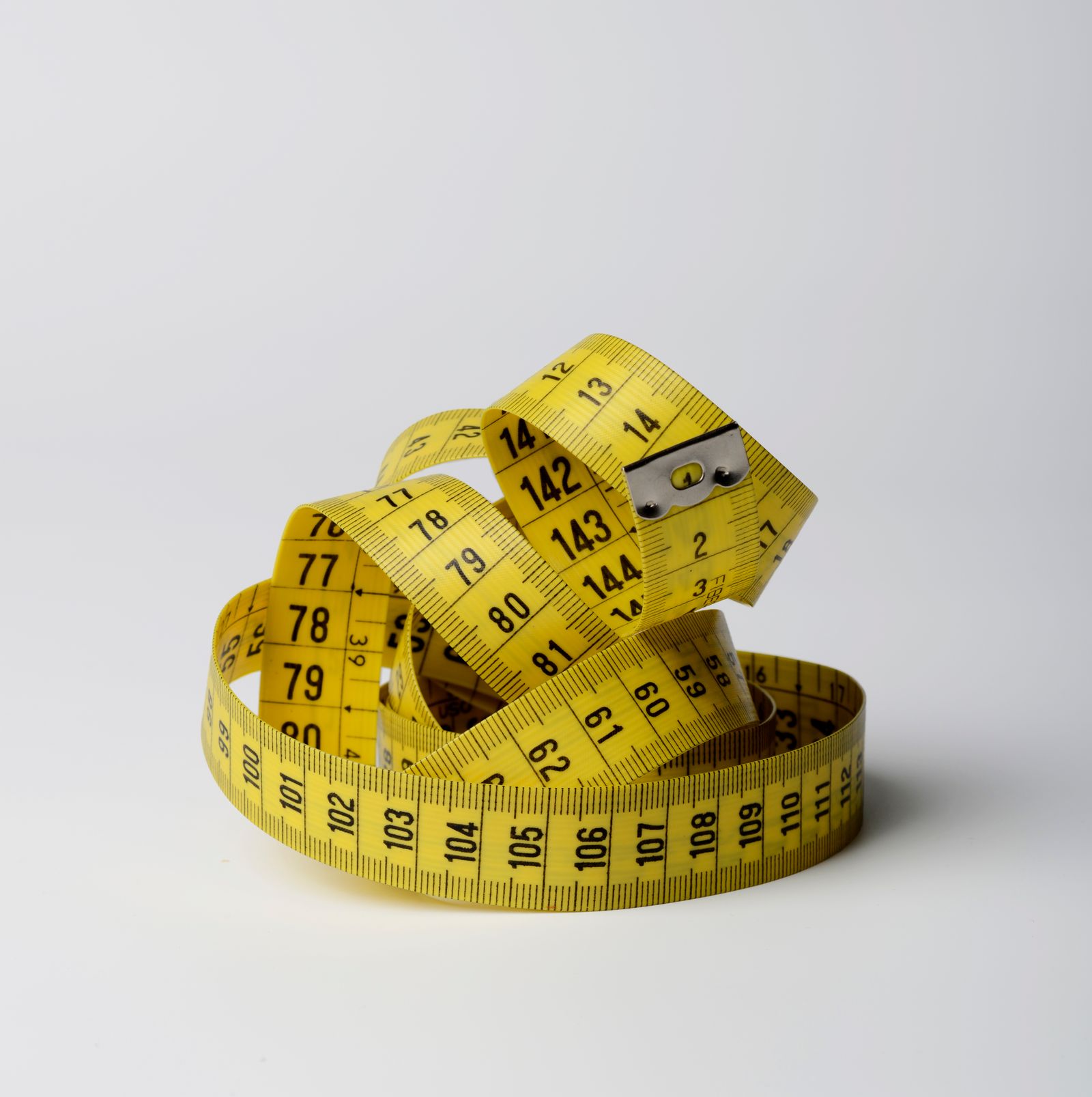 A bright yellow tape measure coiled on a white background