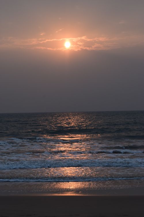Free Peaceful ocean sunset with waves reflecting the warm golden glow of the sun. Stock Photo
