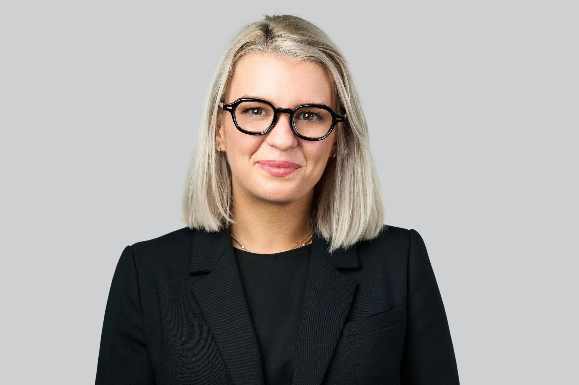 Portrait of a confident businesswoman wearing glasses in a studio setting.