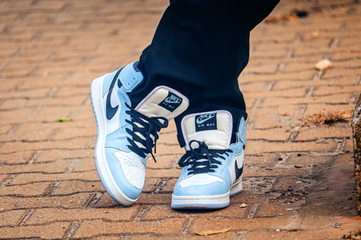 Close-up of fashionable blue and white Nike sneakers on a brick path, showcasing modern street fashion.
