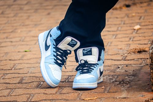 Free Close-up of fashionable blue and white Nike sneakers on a brick path, showcasing modern street fashion. Stock Photo