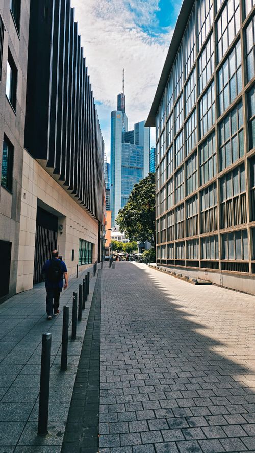 Free A modern city alleyway flanked by skyscrapers under a bright sky, capturing urban life. Stock Photo