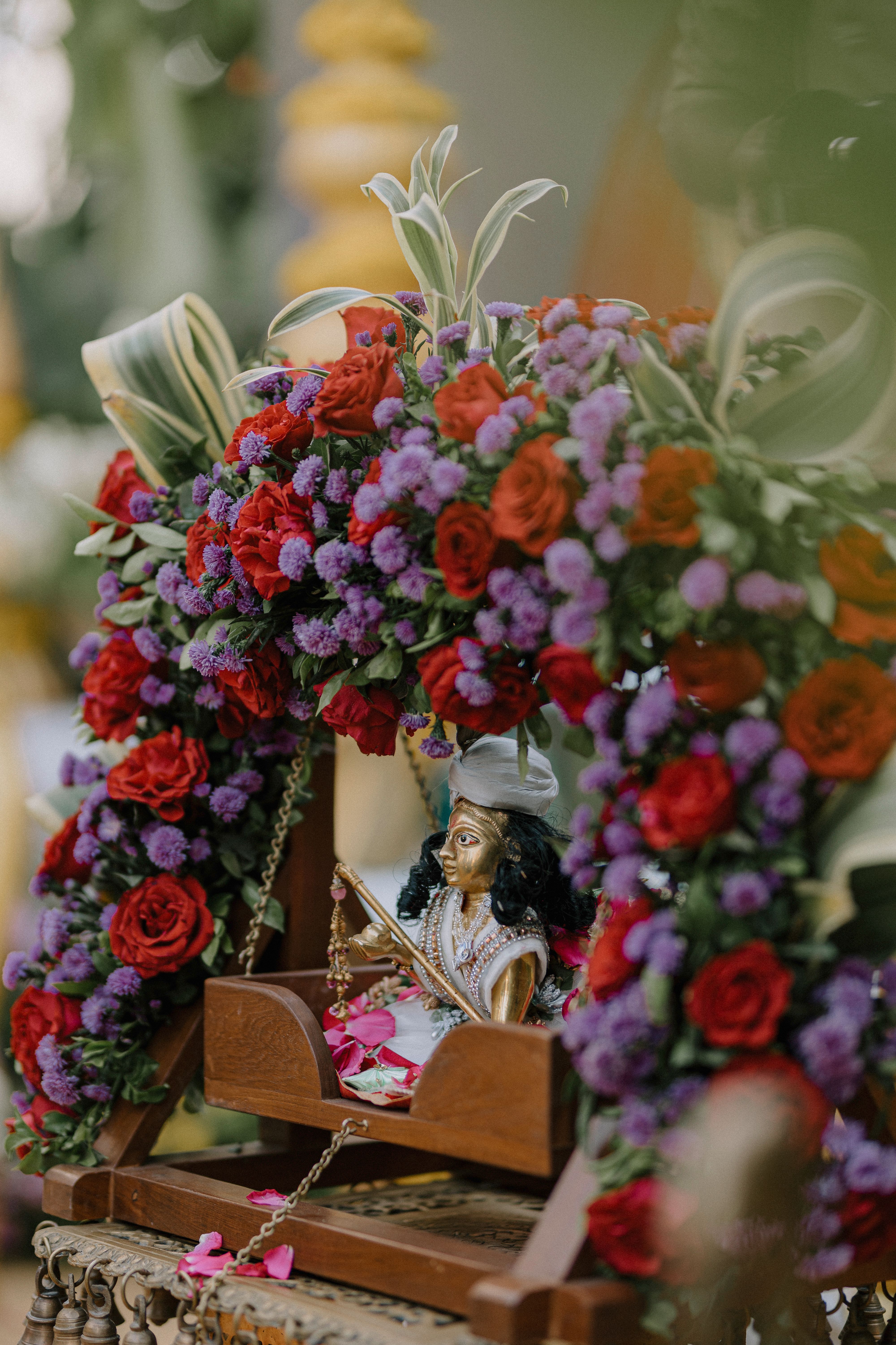 Vibrant Krishna idol adorned with colorful flowers in a traditional setting.
