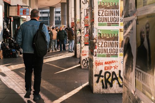 Free A lively urban street scene featuring pedestrians and poster-covered walls. Stock Photo