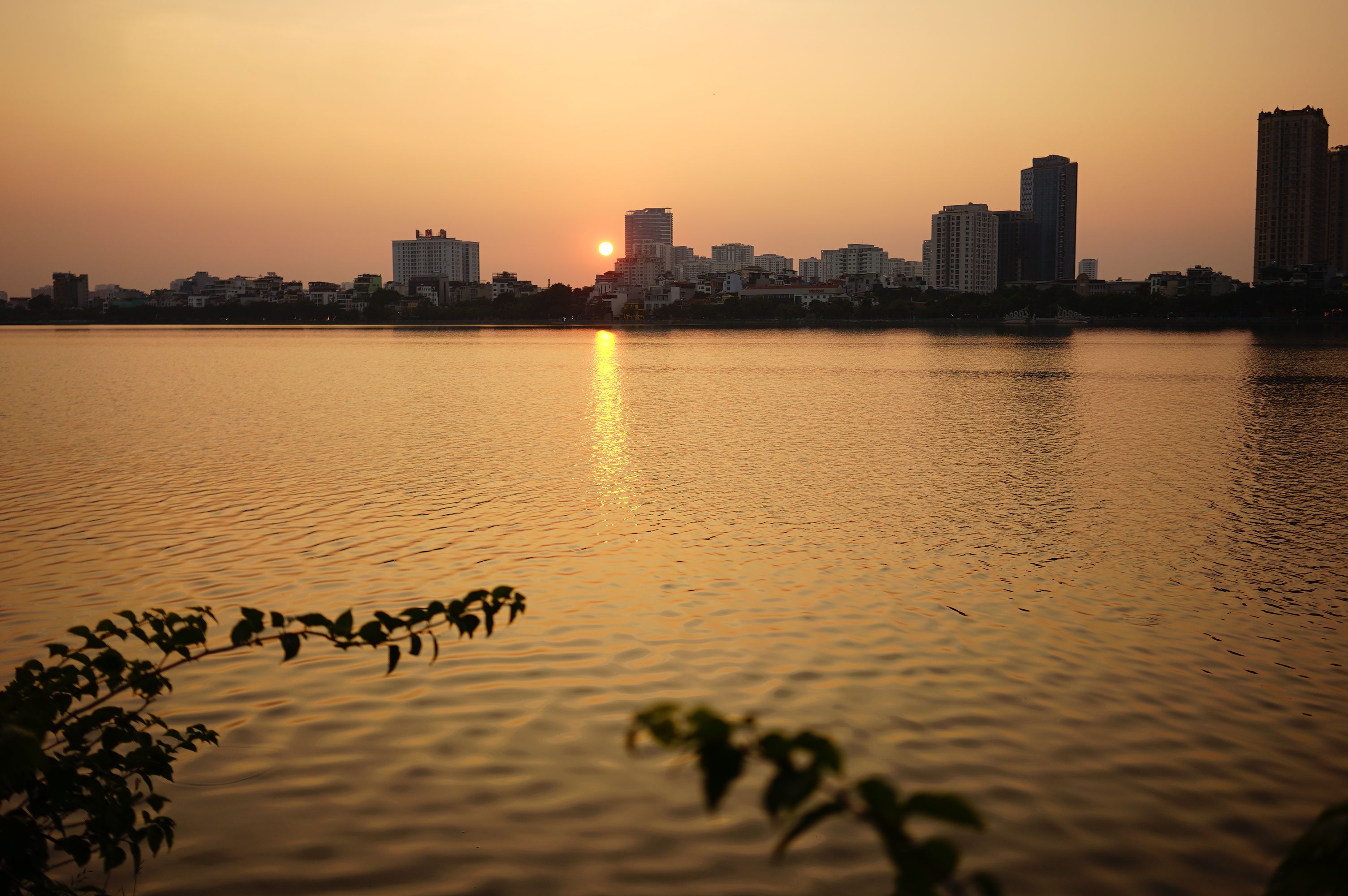 Sunset Over Urban Skyline Reflecting on Calm Lake · Free Stock Photo