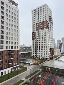 Modern high-rise buildings with basketball courts and pool in urban residential area.
